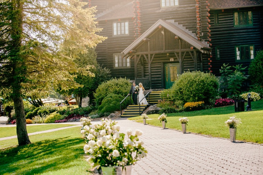 bride is walking on the oath towards ceremony background is chateau montebello building