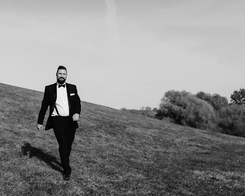 groom is walking down the hill for the ceremony