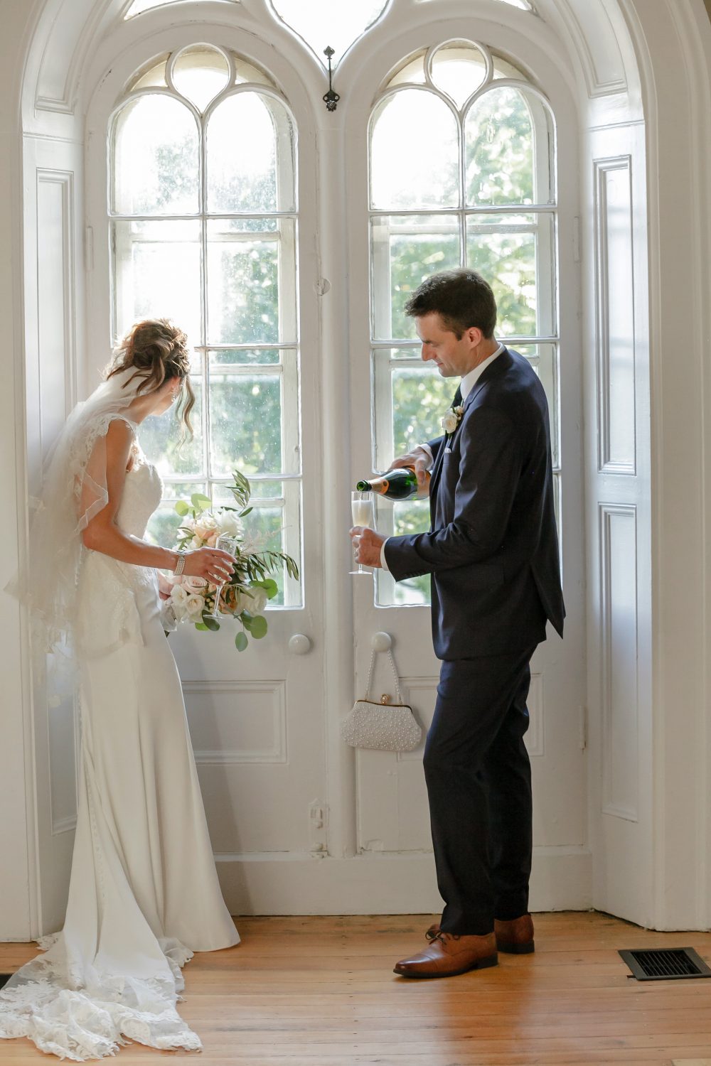 groom is poruing champgane, bride is lokking out the window at strathmere's farmhouse