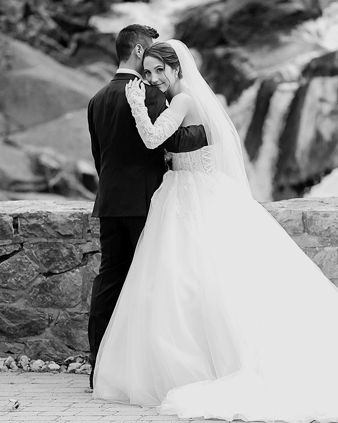 couple standing in front of little waterfall of wakefield mill