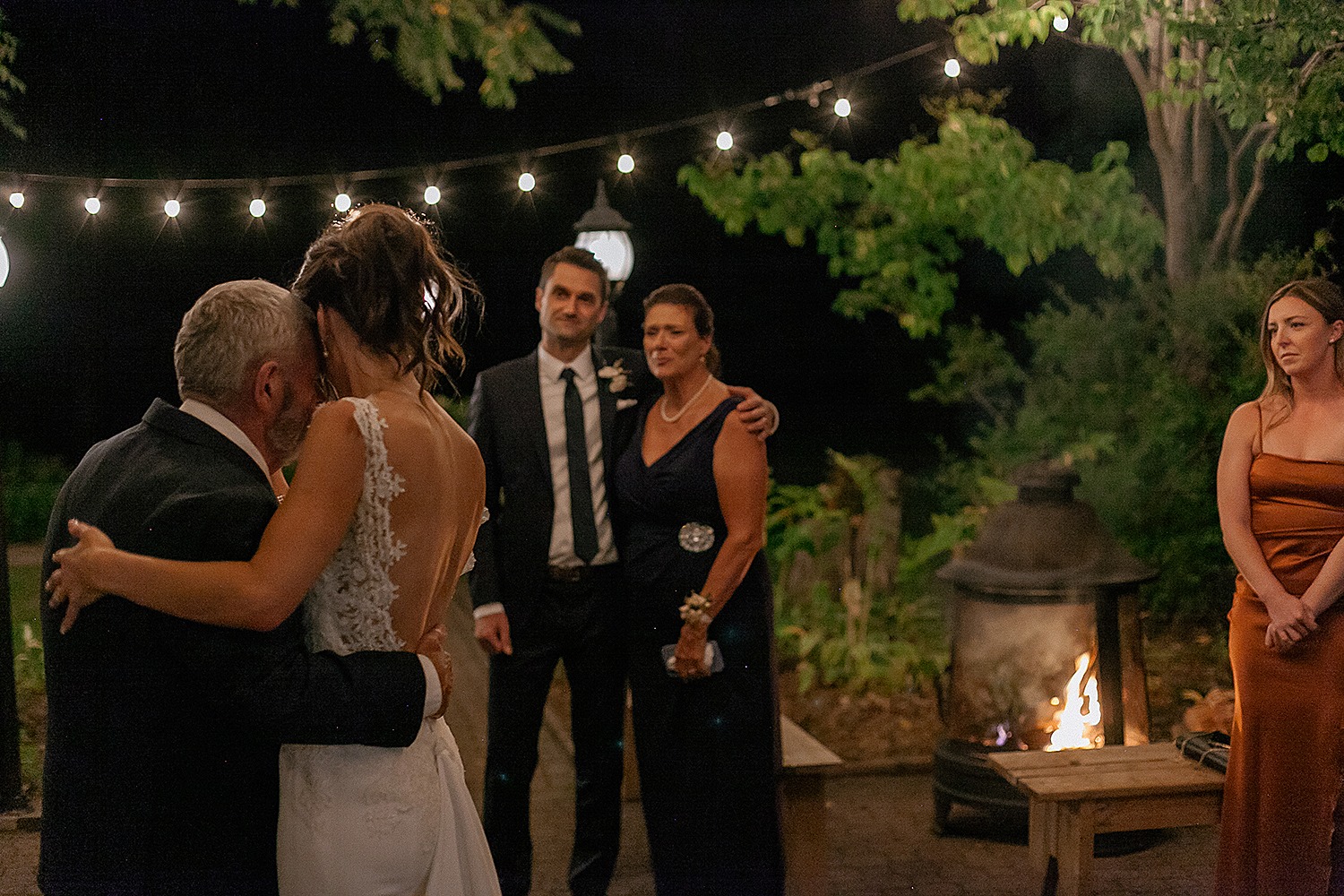 emotional father and bride dances outside of the Farmhouse at strathmere under the light and sky while mom and groom look over at them