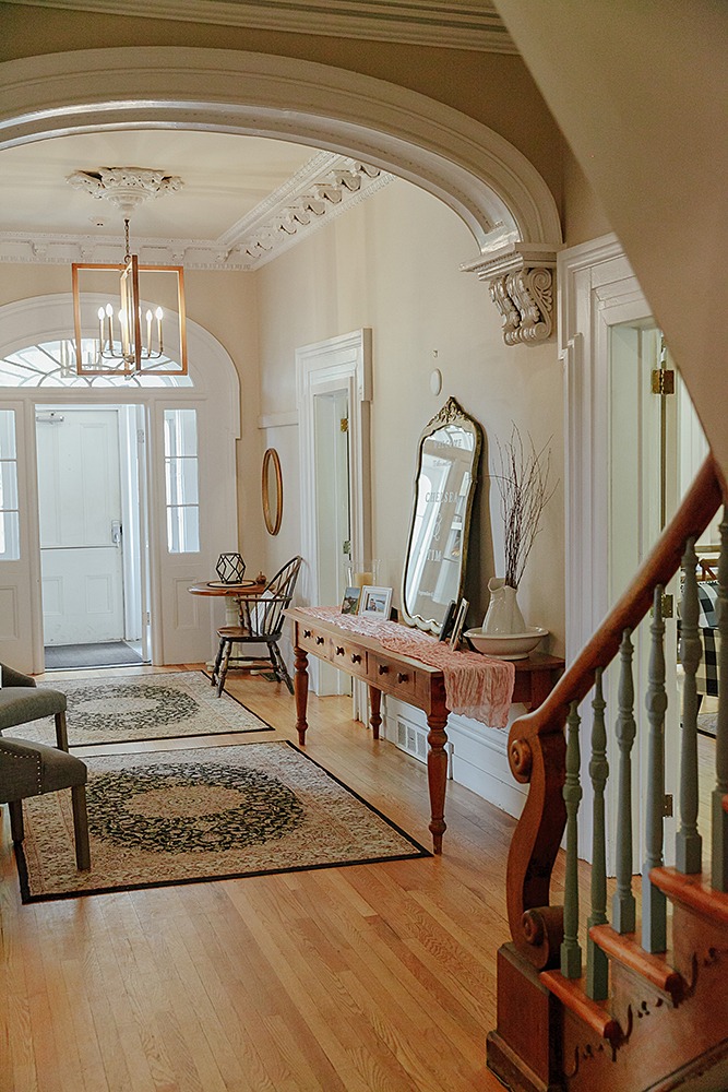 the entrance interior photo at the farmhouse showcasin old wooden staircase , table and mirrir