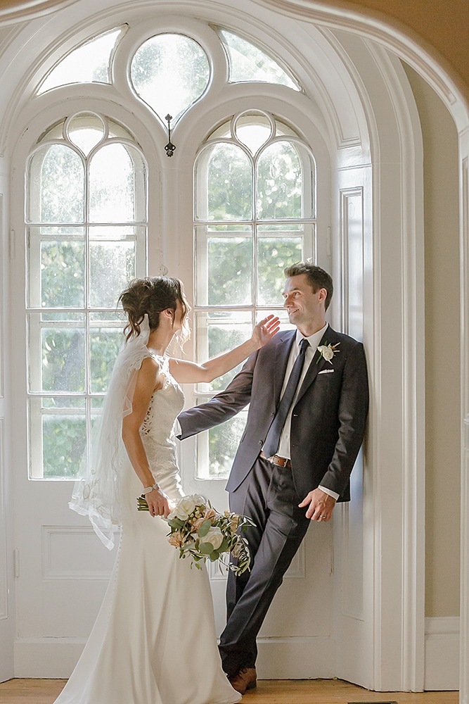 Bride is about to touch groom's face gently while groom is reaching out towards her body
