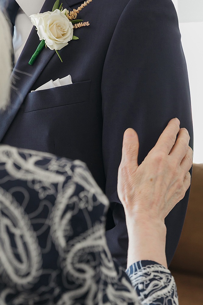 closeup of mom's hand gently touching on groom's arm