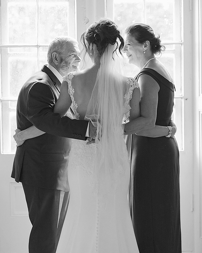 photo of bride surrounded and hugged by her parents from the back. black and white nostalgic athmosphere