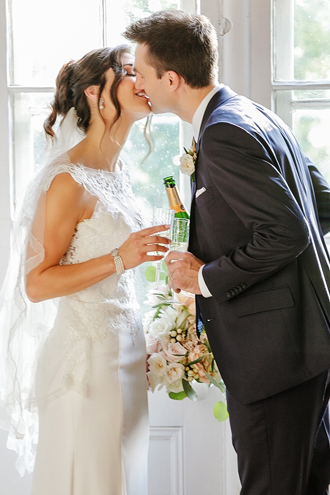 Newlyweds toasting with champagne and sharing a kiss after their wedding celebration