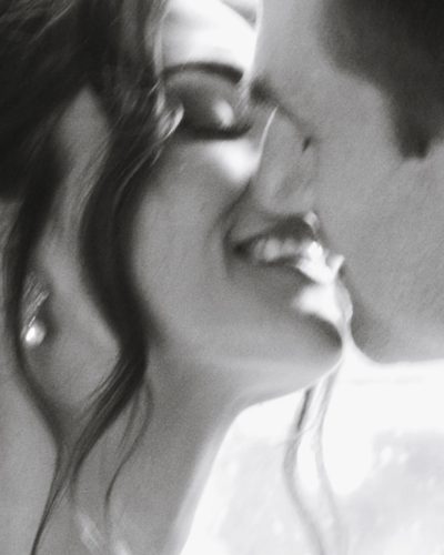 Black-and-white wedding photo of bride and groom sharing a tender near kiss, classic and timeless fine art wedding photography style.Candid wedding moment photographed by Ottawa wedding photographer Eva Hadhazy at a refined celebration in Ontario.