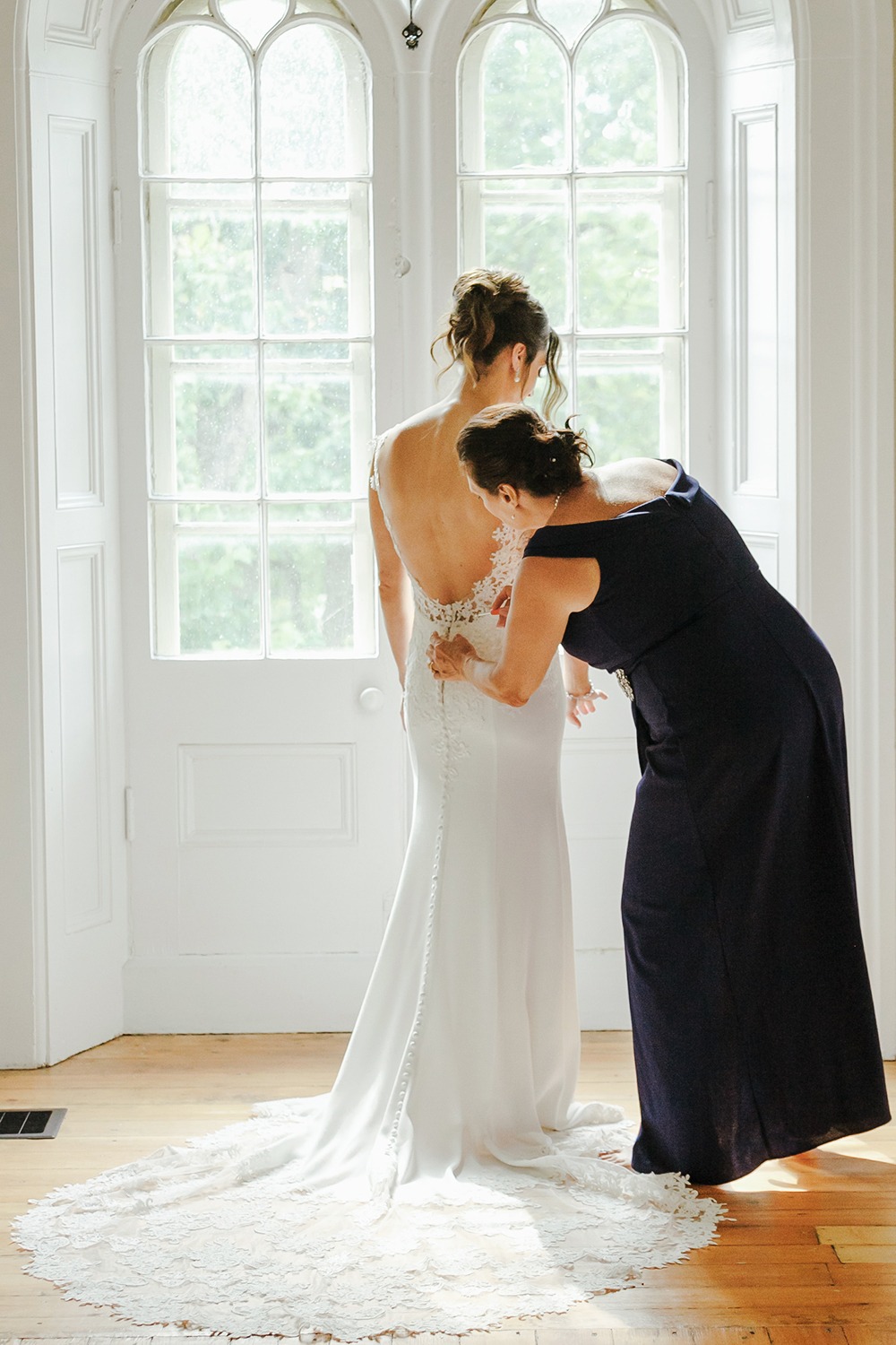 mom is adjusting dress on bride at the back