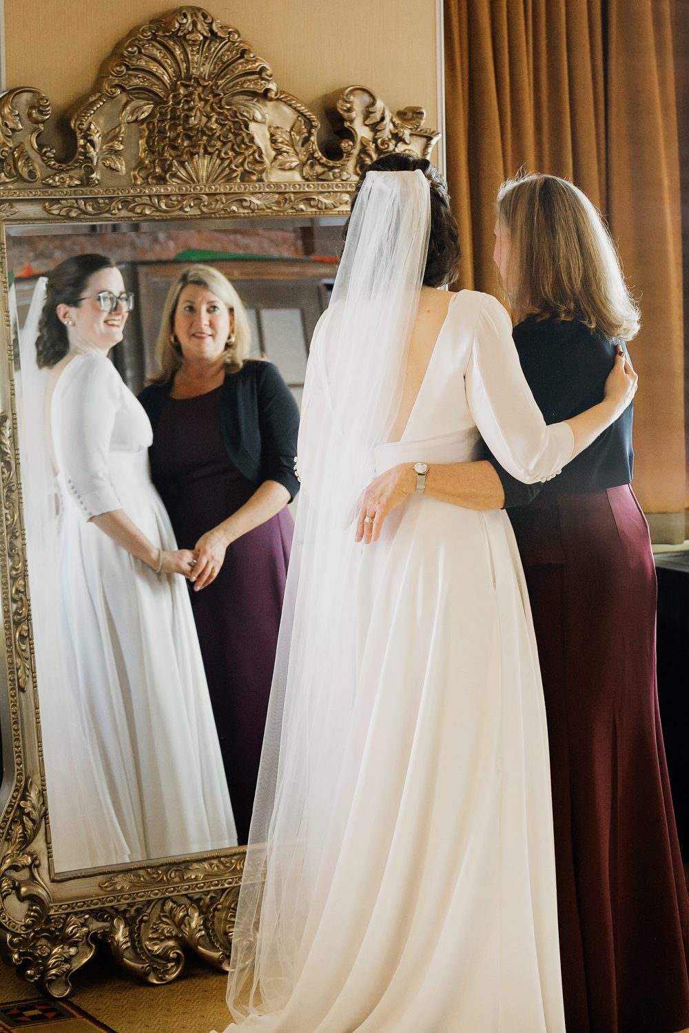 Mom and bride gently huggin each other