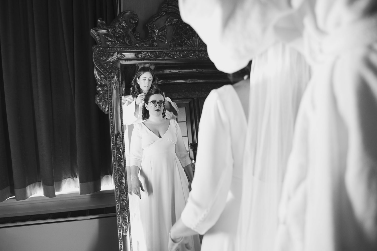 Bridesmaid is placing the veil on the bride