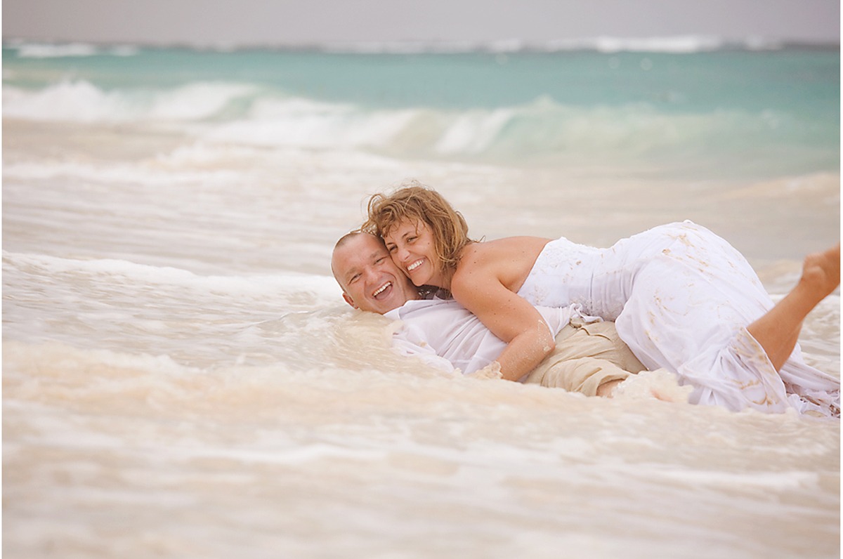 Wedding couple rolling in the ocean in Barbados