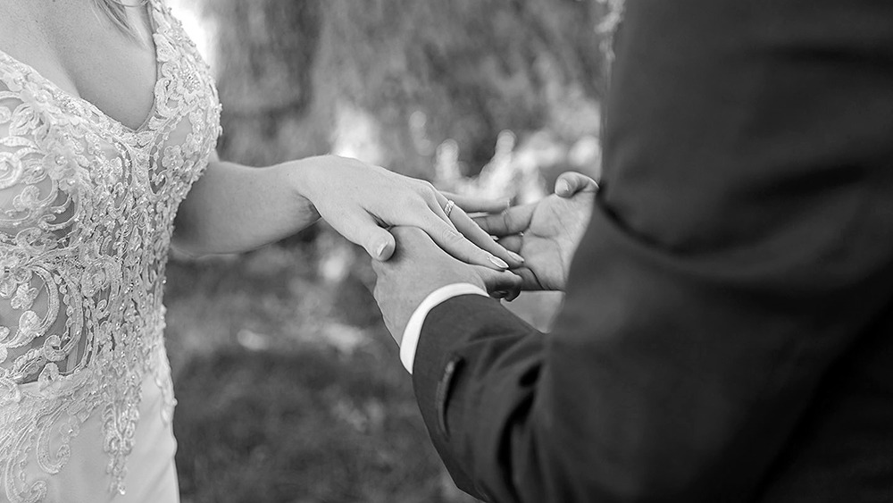 groom is placing the ring on brides finger during an ottawa micro wedding at the arboretum