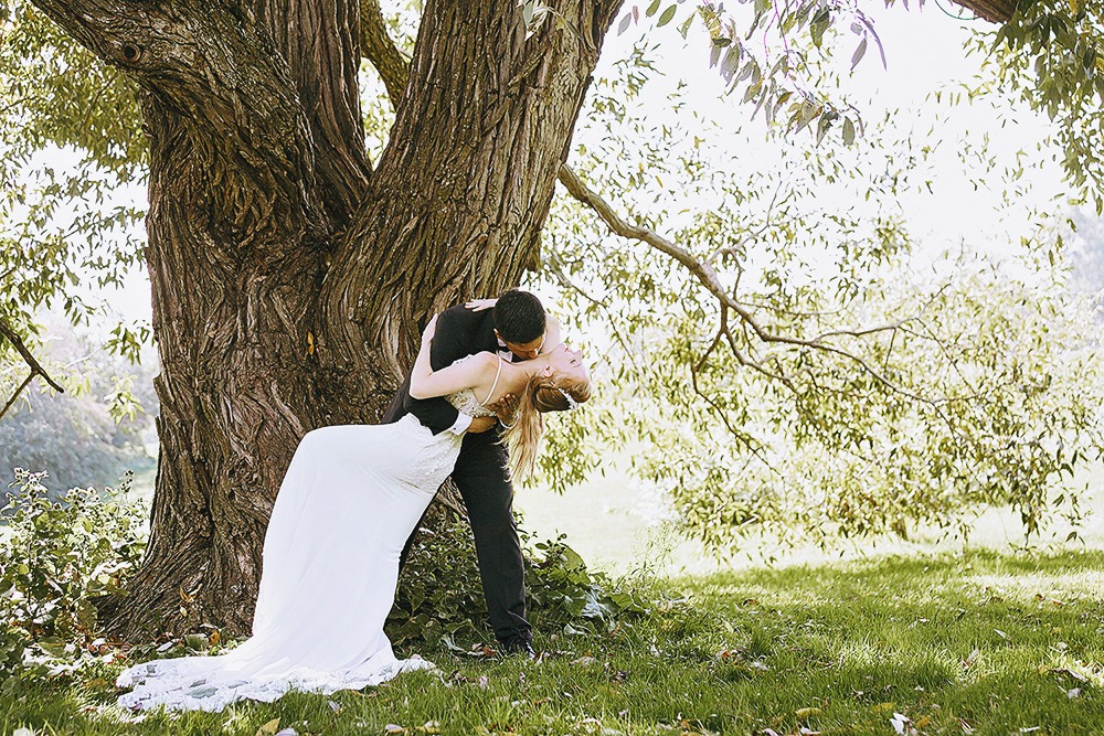 Bride and groom posing for portraits among trees in the Ottawa Arboretum